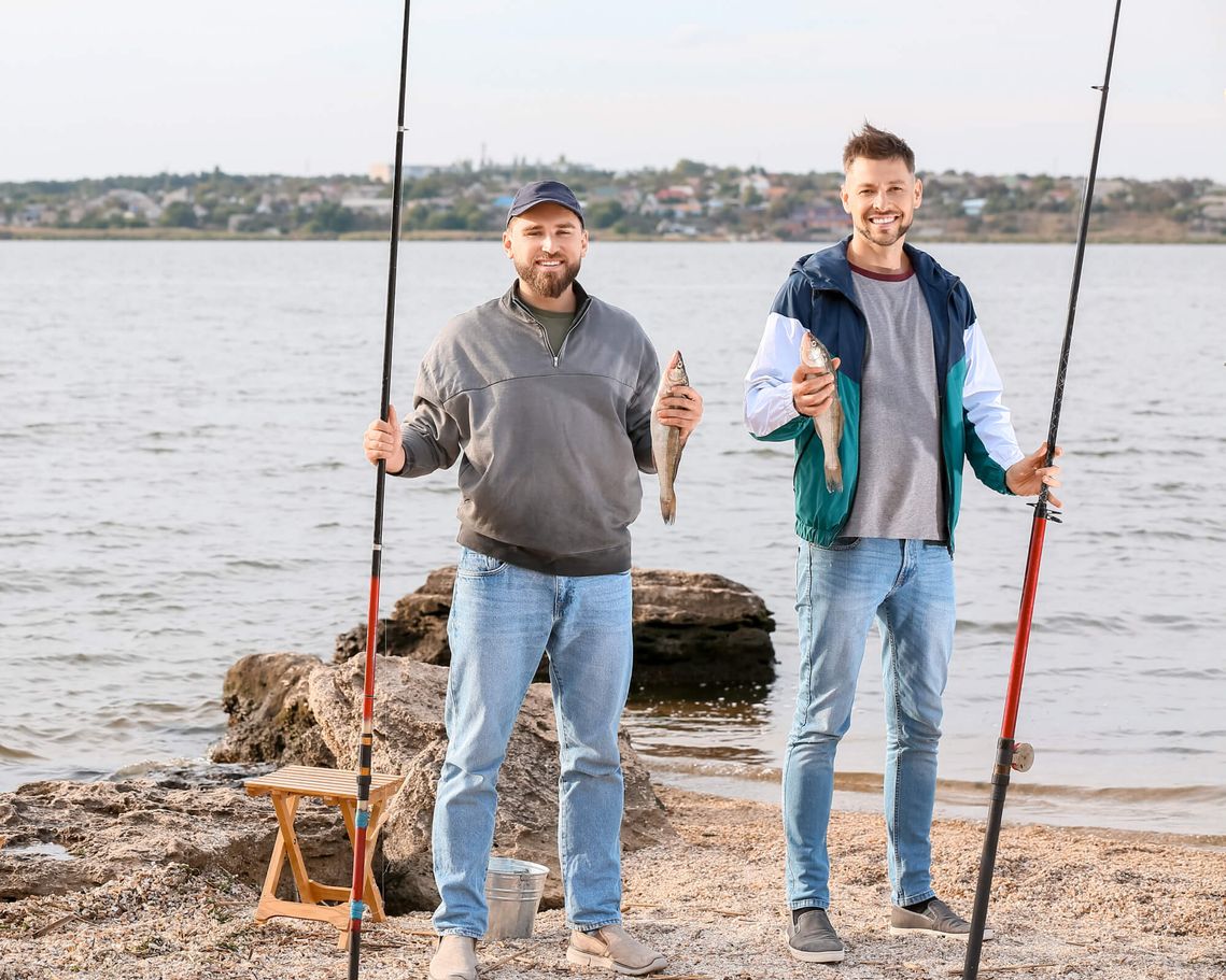 men with fishing rods and caught fish in hand